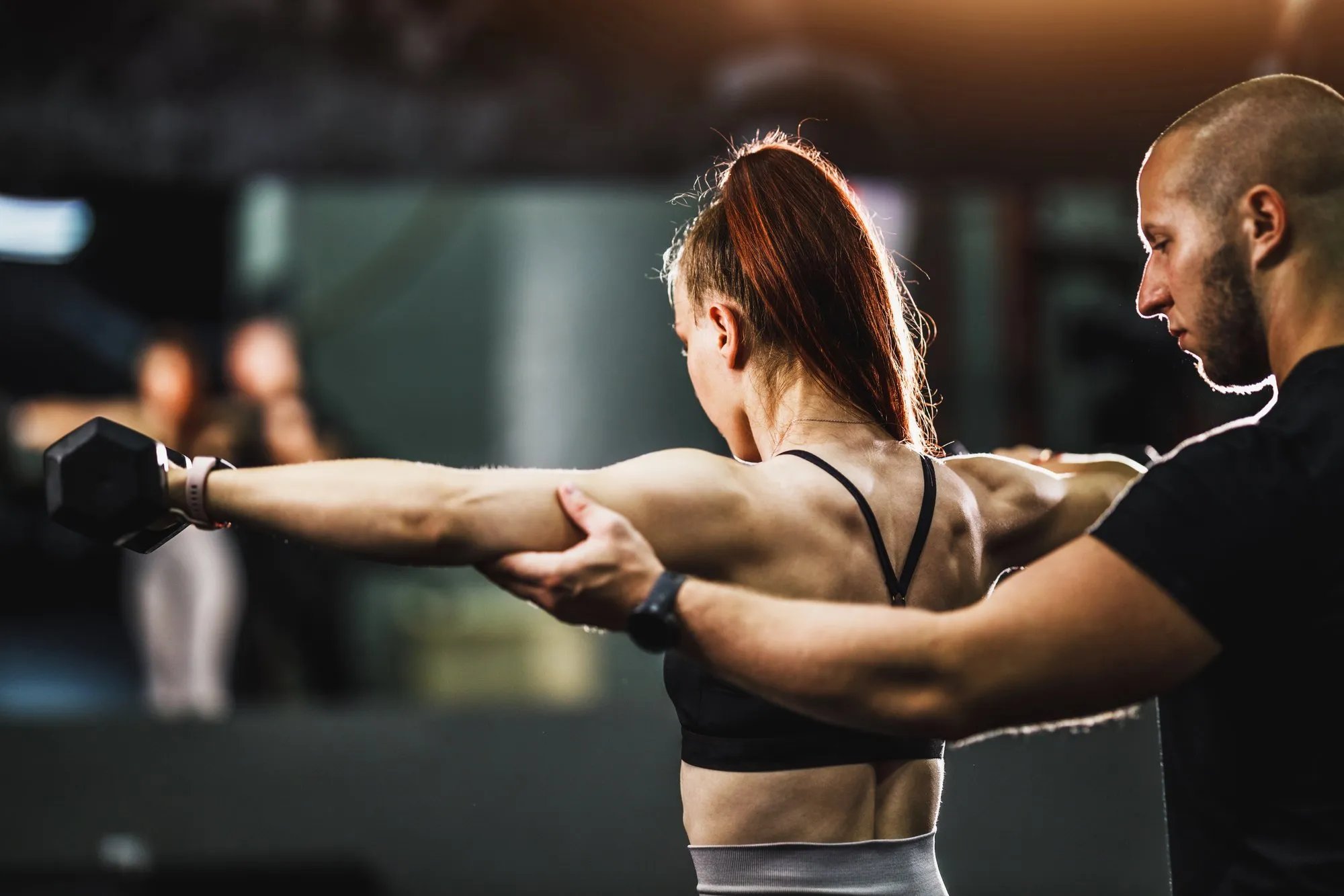 A woman in a black tank top is doing a workout.